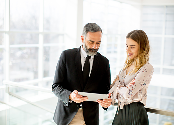 businessman-and-businesswoman-standing-with-tablet-in-office